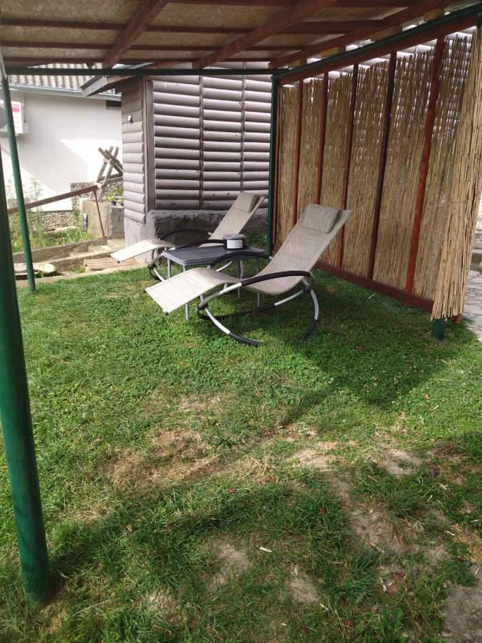Dve ležaljke na travnjaku ispod pergole od drveta i trske