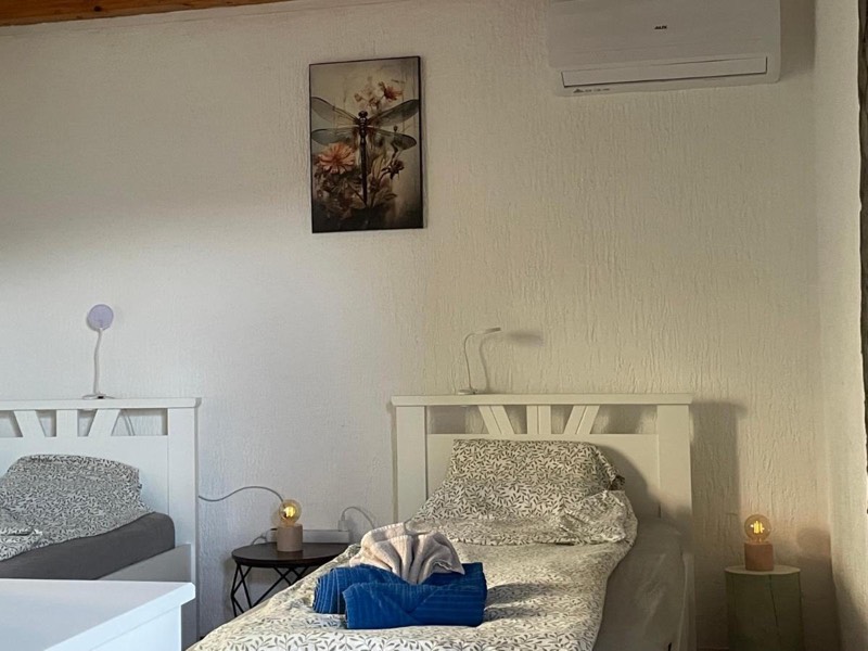 Spavaća soba s dva odvojena kreveta, noćnim lampama, slikom na zidu i klima-uređajem