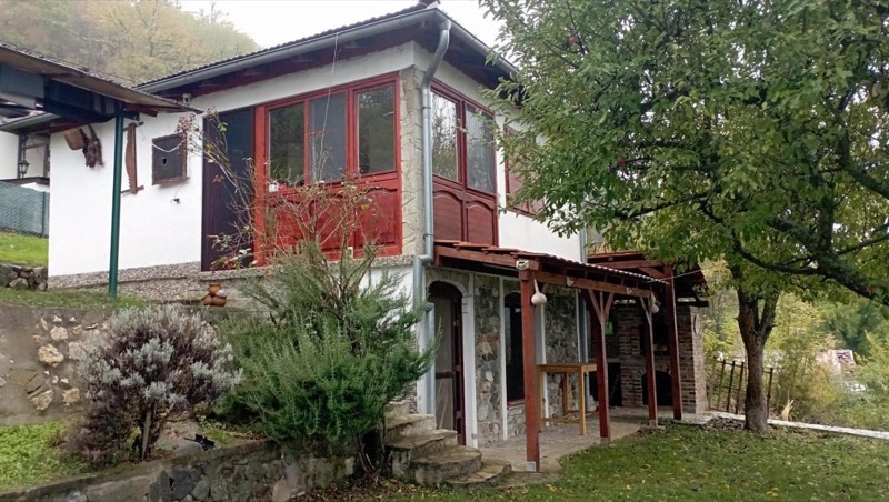 Vila Hedona spreda: beli zidovi, drvena veranda boje crvenog drveta, bašta s lavandom i voćkom